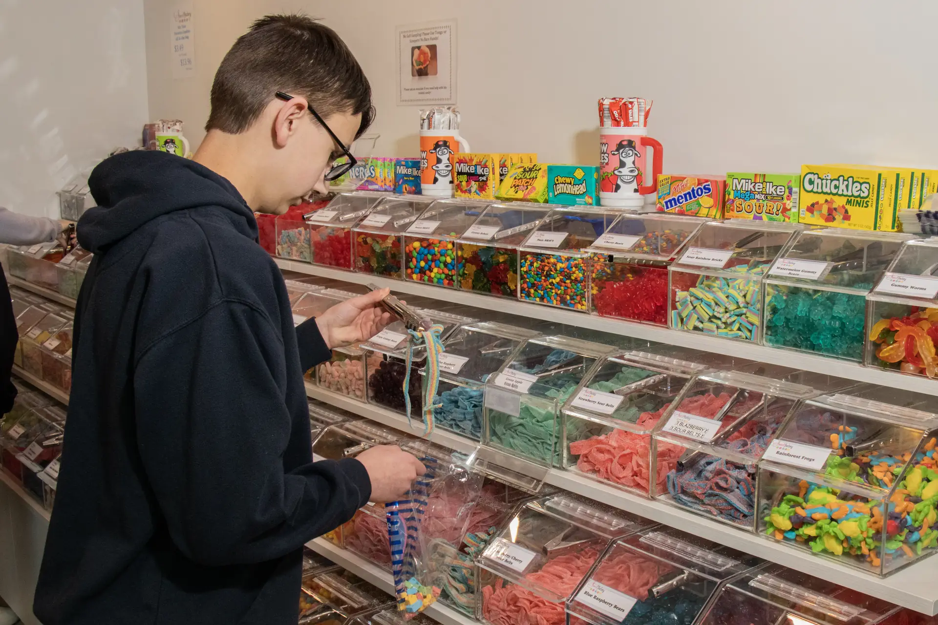 Teen boy with glasses browsing candy at Sweet Factory, Somerset Mall