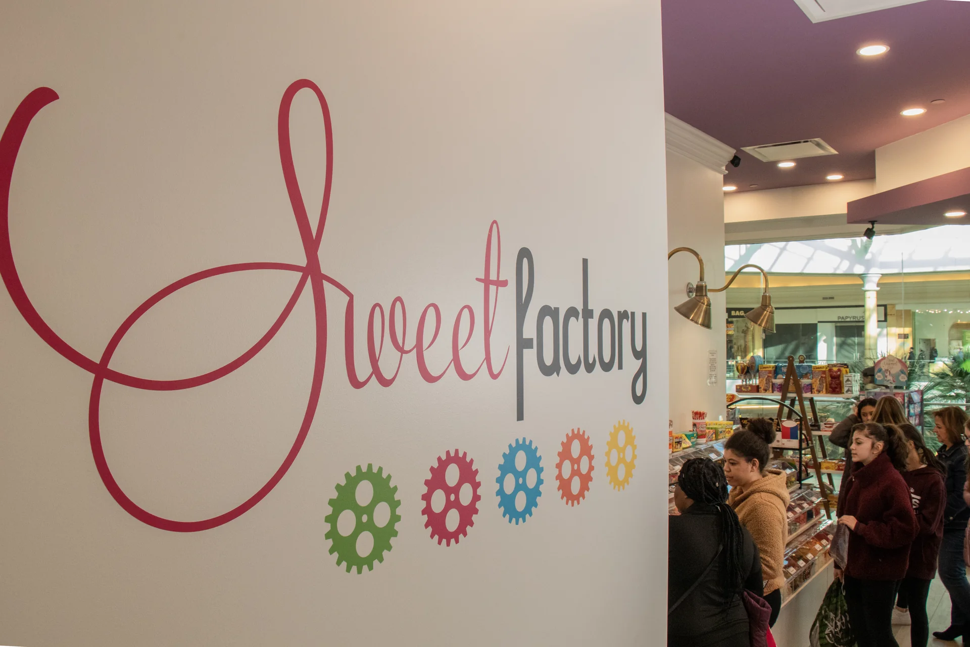Sweet Factory logo wall mural with customers browsing candy at Somerset Mall, Troy Michigan